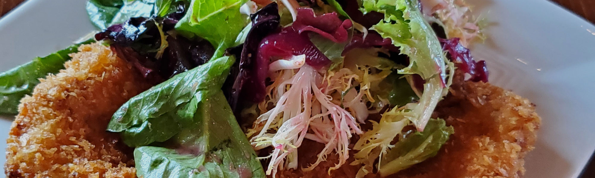 A crisp panko-crusted cutlet topped with dressed mixed greens