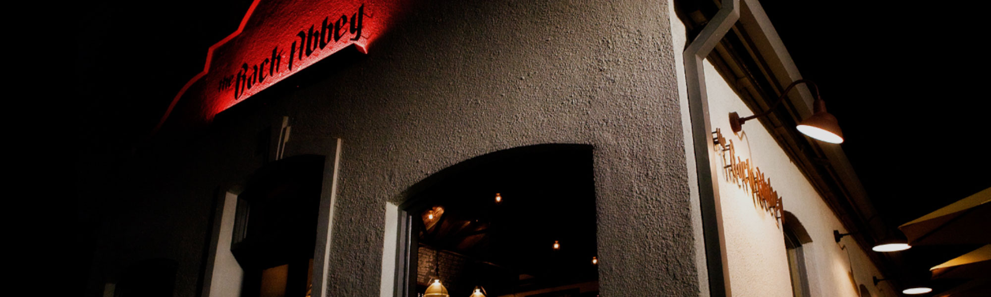 The Back Abbey's red illuminated sign above the entrance at night